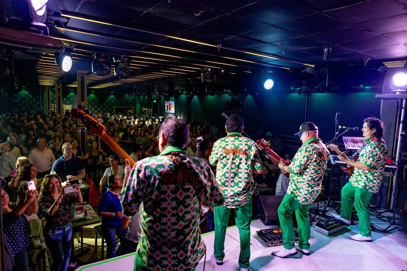 Band performing in matching outfits under the stage lights at a LIVEST show.